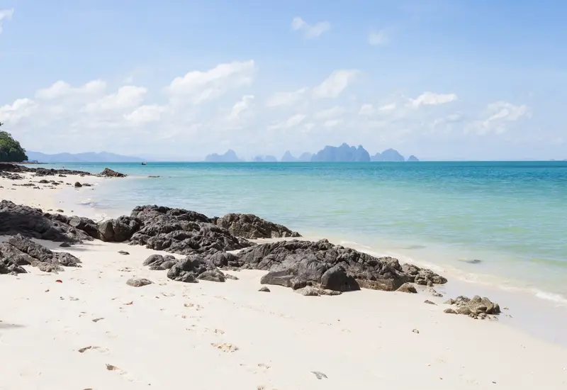White-sand beach and turquoise sea in Phuket with karst islands on the horizon (photo: Diego Delso / Wikimedia Commons, CC BY-SA 3.0)